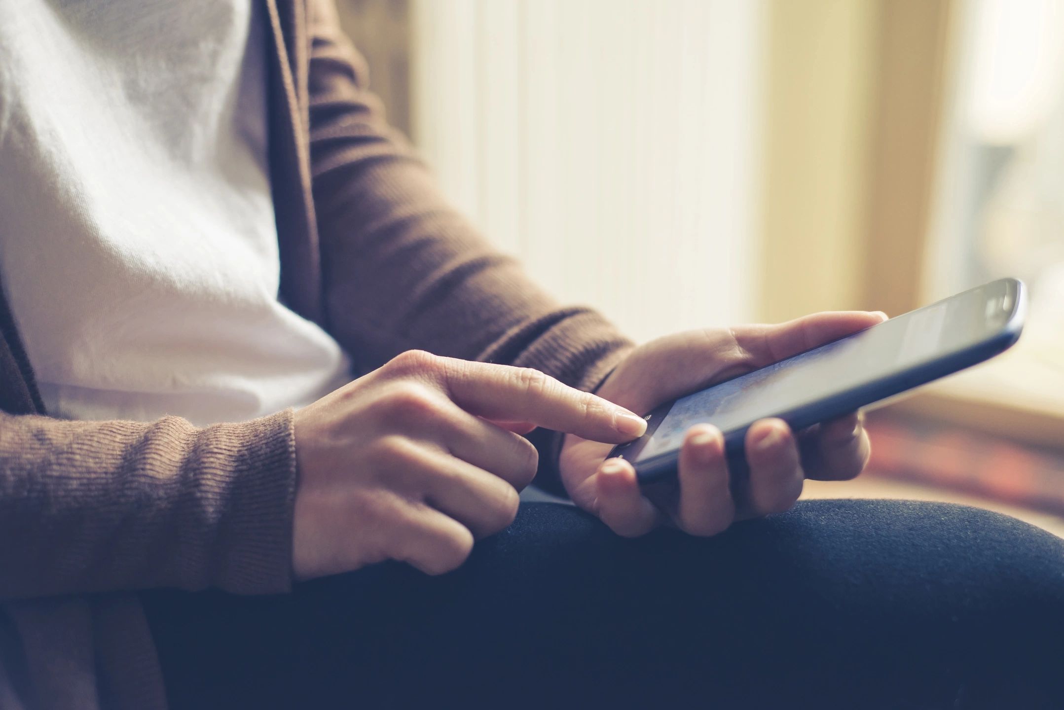 Close-up of a hand dialing on a smartphone in a calm, safe environment, symbolizing connection and accessibility